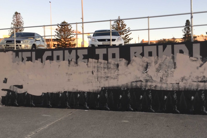 A black mural of border force agents painted over with white paint.