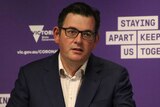 Victorian Premier Daniel Andrews motions as he speaks, with a purple "Staying Apart Keeps Us Together" logo in the background.