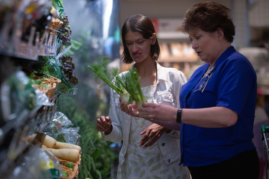 Two women in a supermarket looking at fruits and vegetables