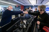 two NASA engineers bump fists in celebration of the James Webb Space Telescope overcoming the riskiest part of its mission