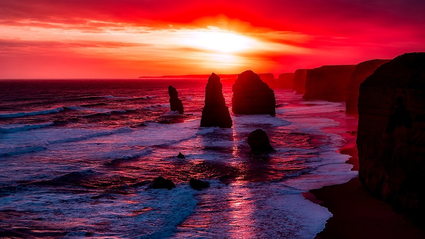 The Twelve Apostles in Australia with the setting sunset in the background and a red sky