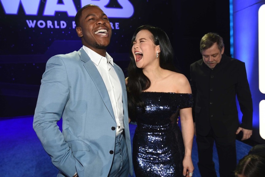 Two people laughing dressed in a suit and a sparkly dress