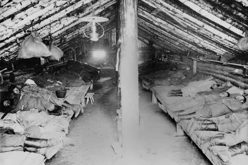Convicts sleep inside of a sod covered house in a Siberian gulag.