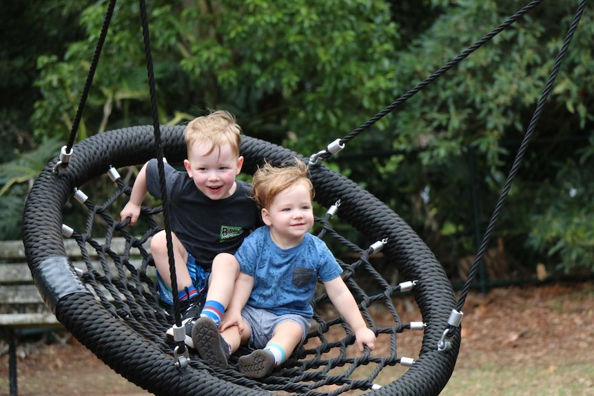 Brothers Micah and Luther Wolnizer play on a swing