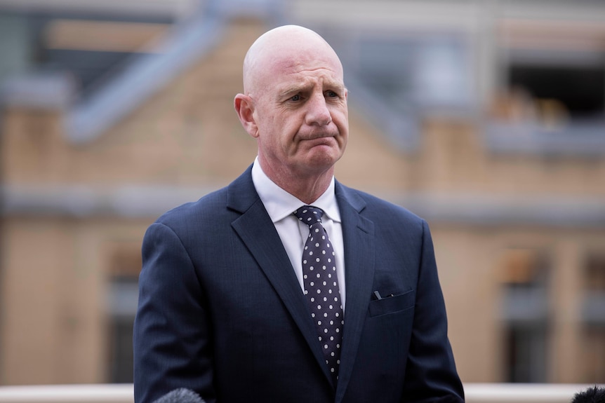 A bald man wearing a suit and spotty tie.