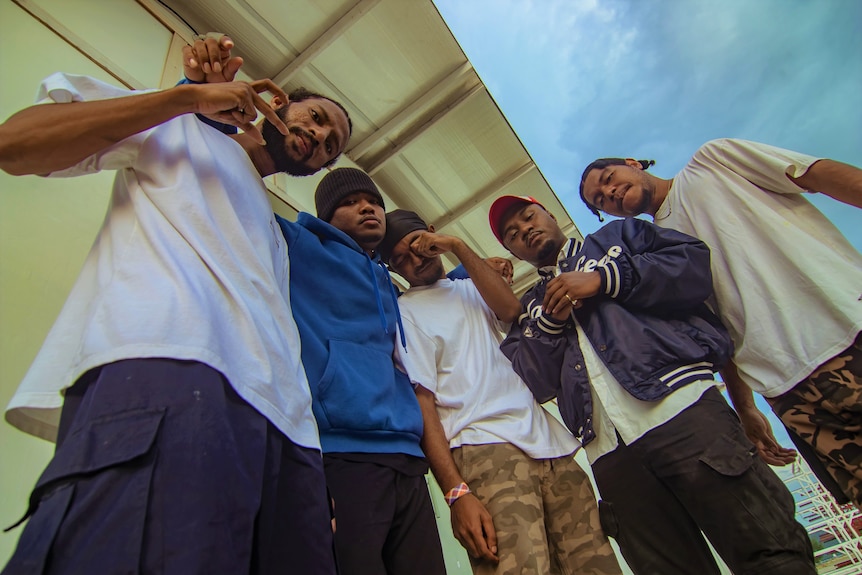 A group of six men looking at the camera with an angle from the ground