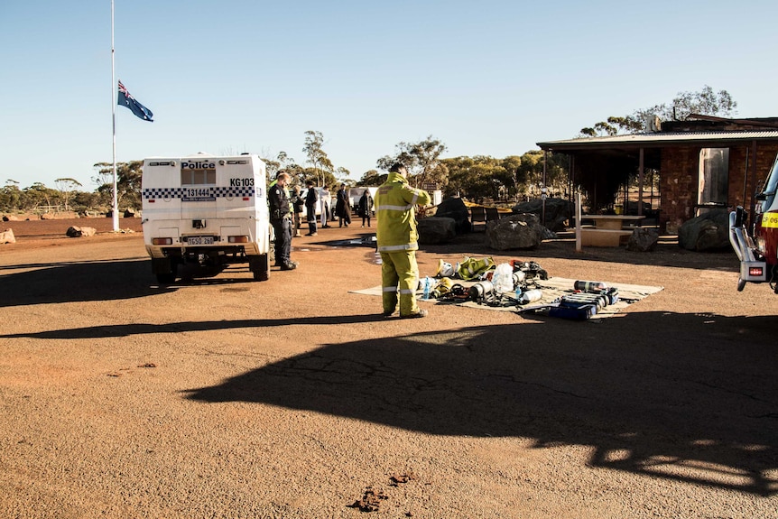 Police, firefighters and onlookers stand in front of pub which was destroyed by fire.