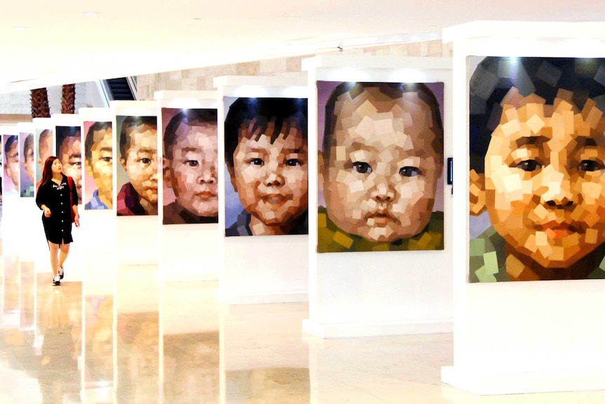 A woman walks past portraits of missing children during an exhibition