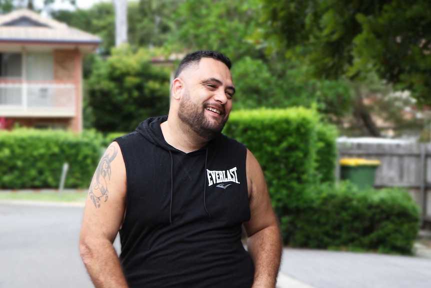 Man in black singlet looks off to the side.