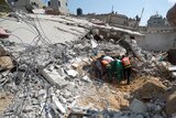 Palestinian Civil Defence workers search for survivors amidst the rubble of a building destroyed in an Israeli air strike, in Gaza City.