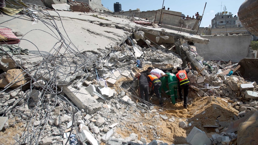 Palestinian Civil Defence workers search for survivors amidst the rubble of a building destroyed in an Israeli air strike, in Gaza City.