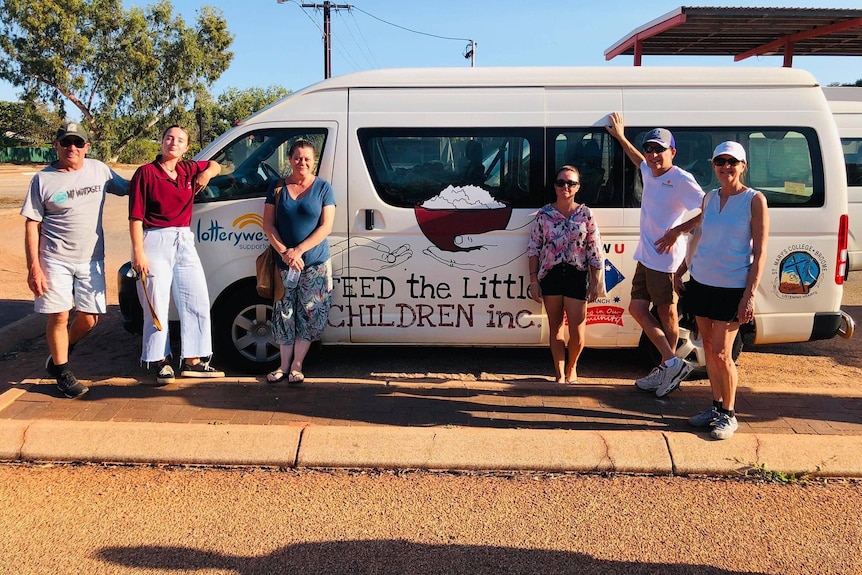 A group of six men and women stand in front of a van branded with the name a of food relief charity.