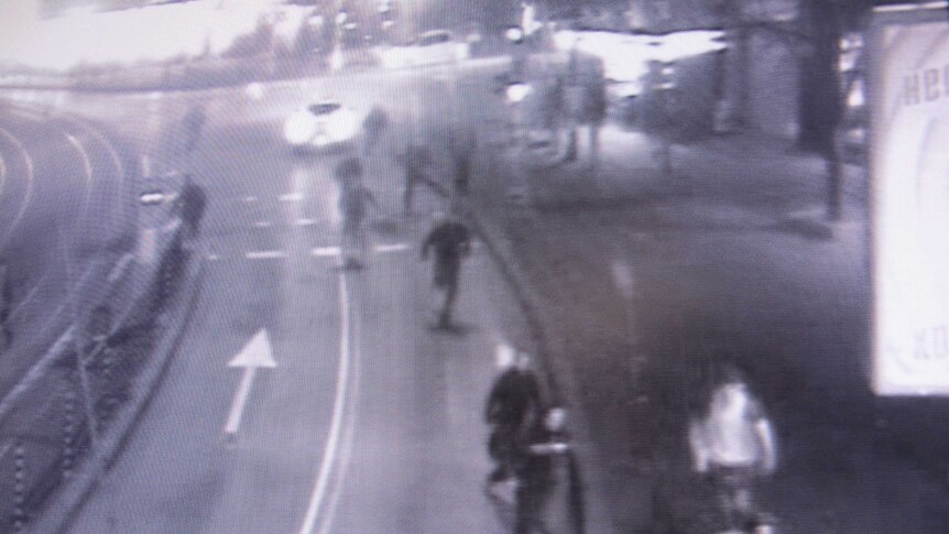 A slightly fuzzy still from CCTV showing a group of people running down a street