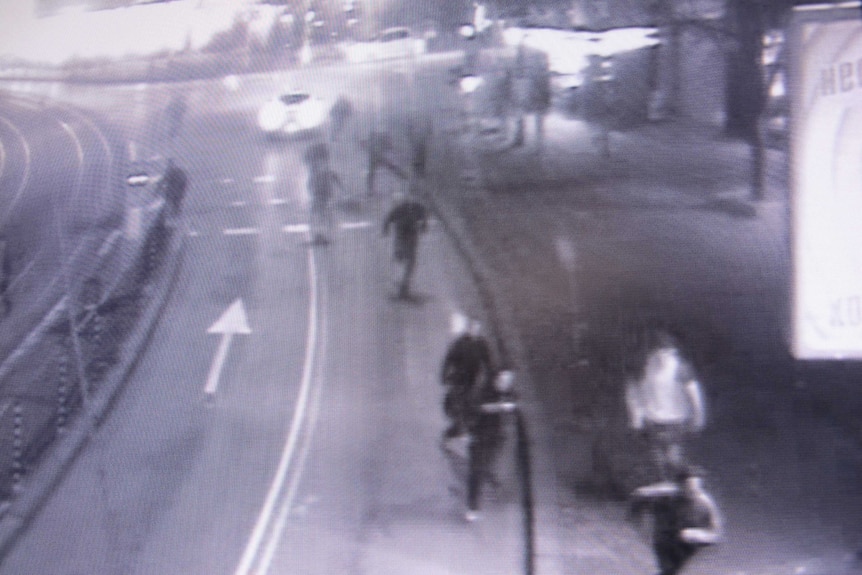 A slightly fuzzy still from CCTV showing a group of people running down a street
