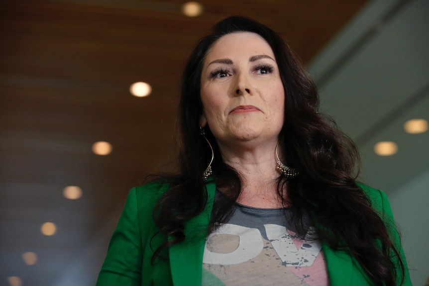 A low shot of a woman with long brown hair wearing a green jacket