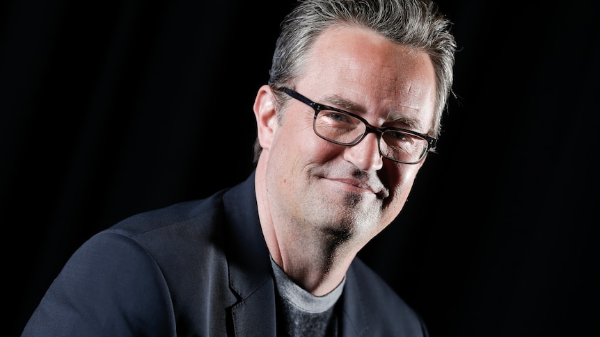 a headshot of a man with grey hair and glasses smiling at camera 
