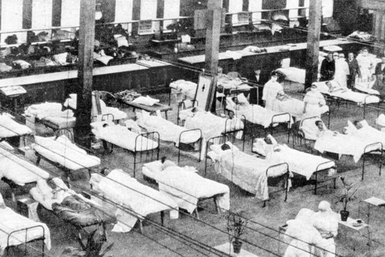 A black and white image of a makeshift hospital in a large hall.
