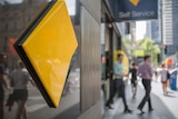 Commonwealth Bank logo with people walking in the background.