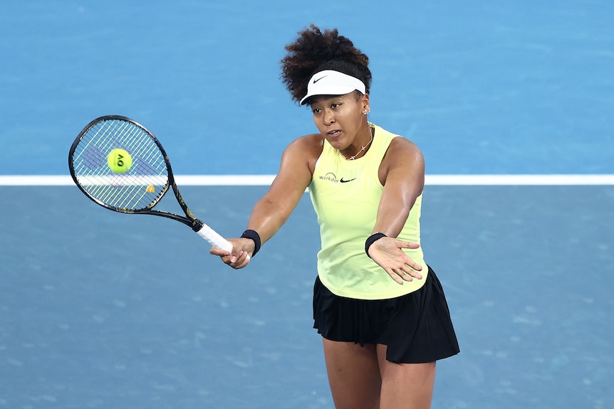 Naomi Osaka's hair flies up as she brings her racquet up to hit a forehand volley.