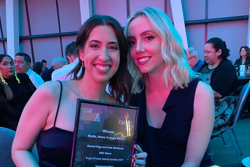 Two smiling women hold an award at an awards night