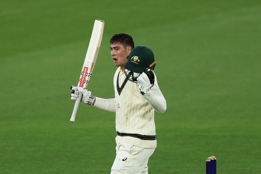 Matt Renshaw raises his bat and holds his helmet in the other hand