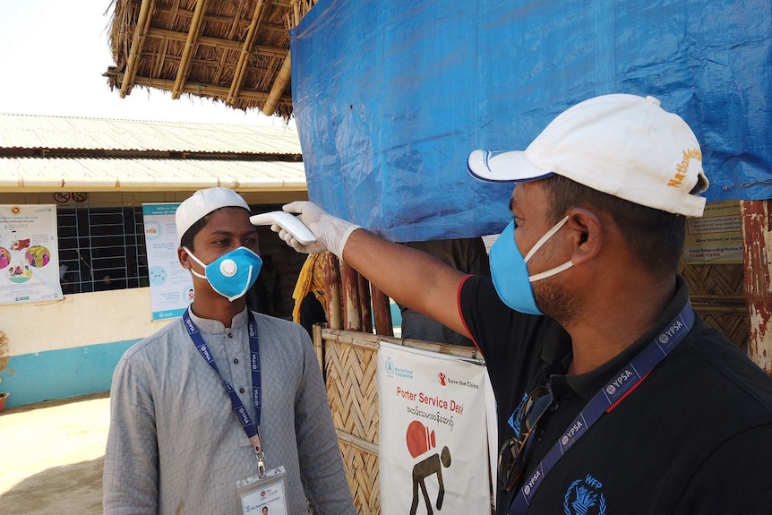 A man uses a handheld thermometer to take another man's temperature