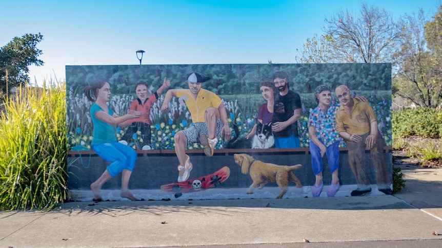 A wall mural in a Point Cook park showing a range of people sitting and doing activities. 