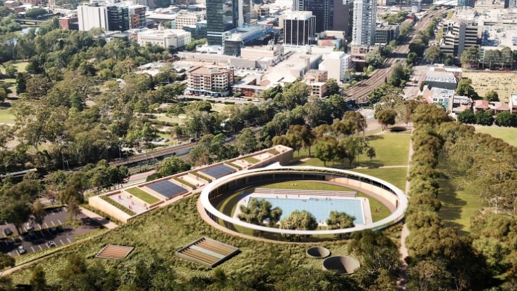 A circular aquatic centre from above, surrounded by trees.