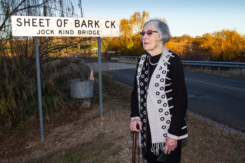 Woman standing at the Sheet of Bark Creek sign.