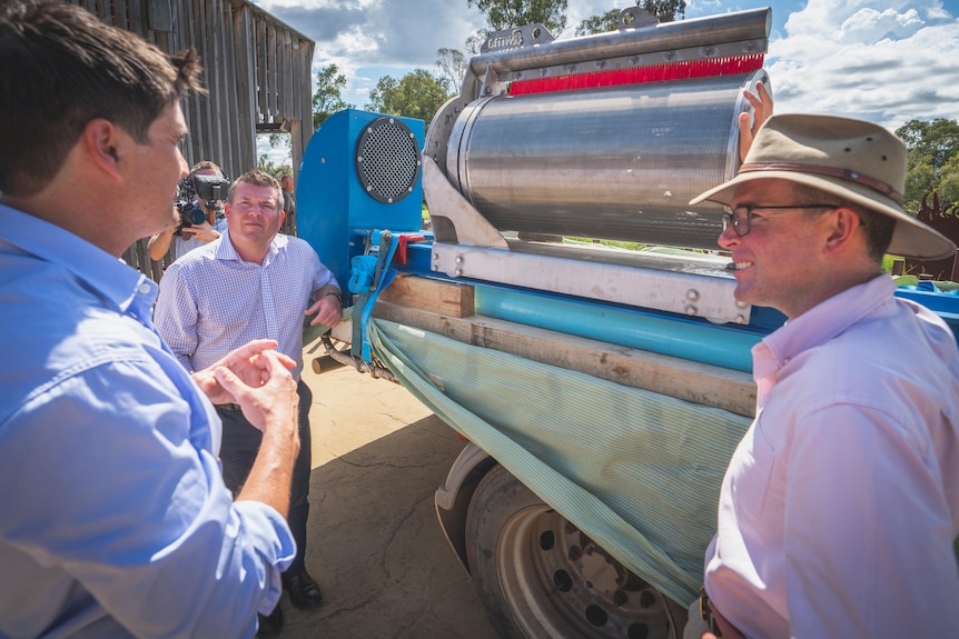 Three men examine a barrel shaped fish screen for an irrigation pump