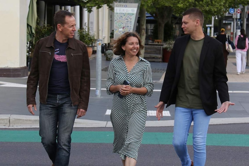 Three Greens members cross the street.