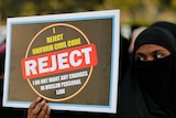 A Muslim woman holding a sign saying I reject uniform civil code, I do not want changes in Muslim personal law.