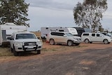 Caravans and cars parked under a cloudy sky