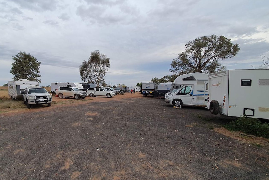 Caravans and cars parked under a cloudy sky