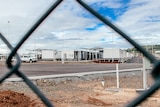 Wide photo of accomodation facility looknig through fence