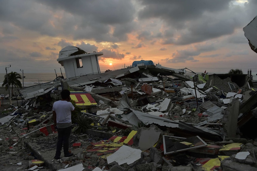 Sun sets as a man stands near rubble in Pedernales