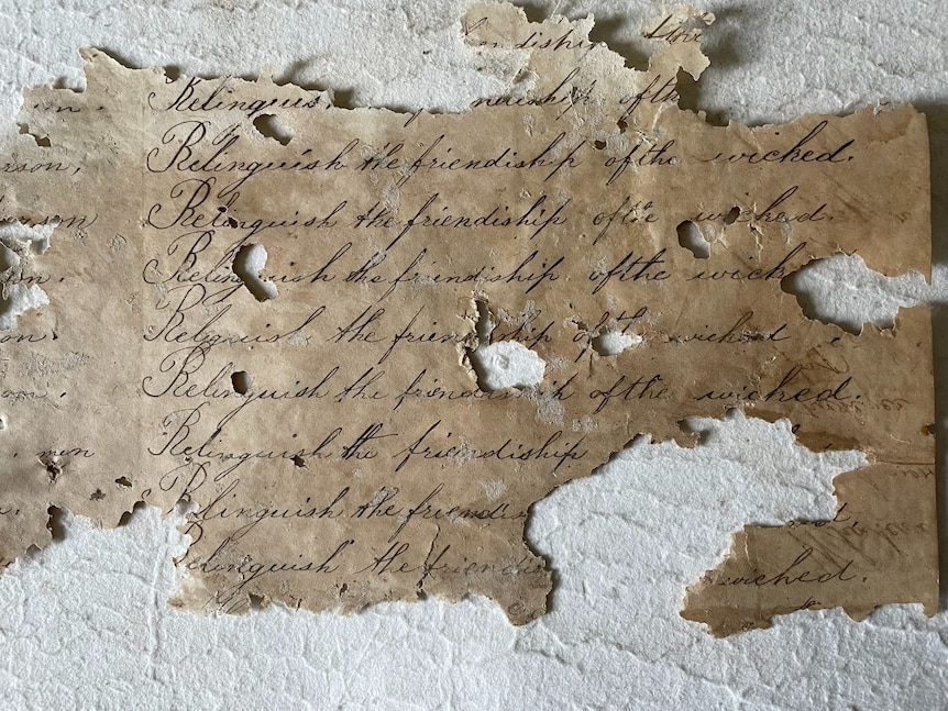 old homework that says 'belinquish the friendship of the wicked' used as wallpaper in an old cottage