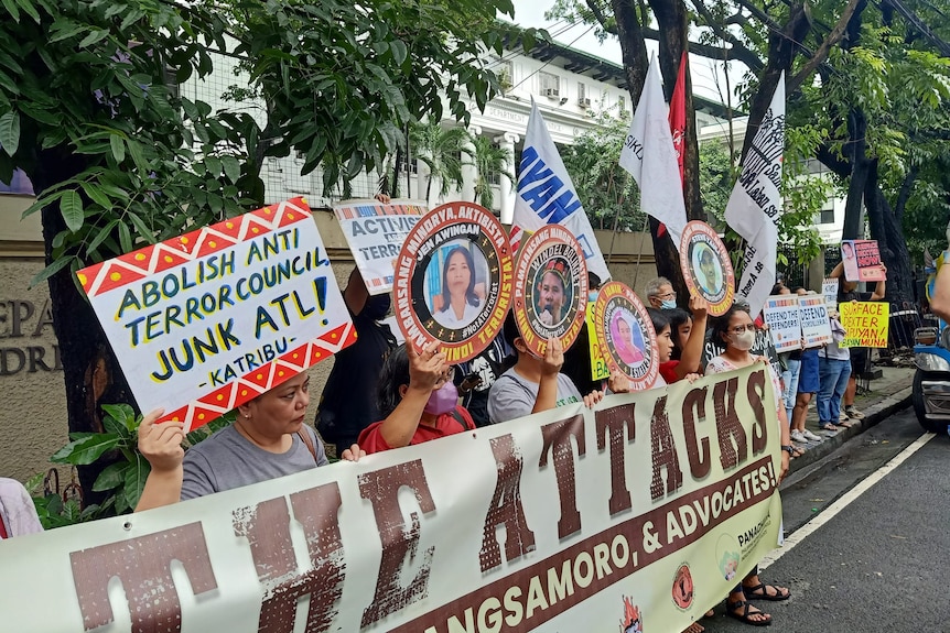 Protesters hold up placards calling to abolish the anti-terror council and faces of disappeared activists