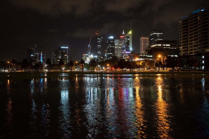 The Perth CBD skyline and Langley Park at night, with the Swan River in the foreground.