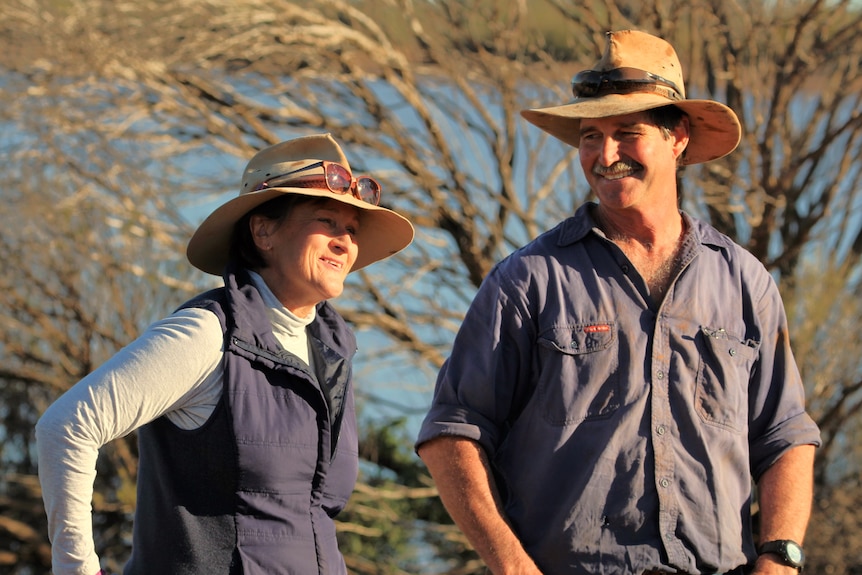 a man and woman in a paddock, the man wears a large hat