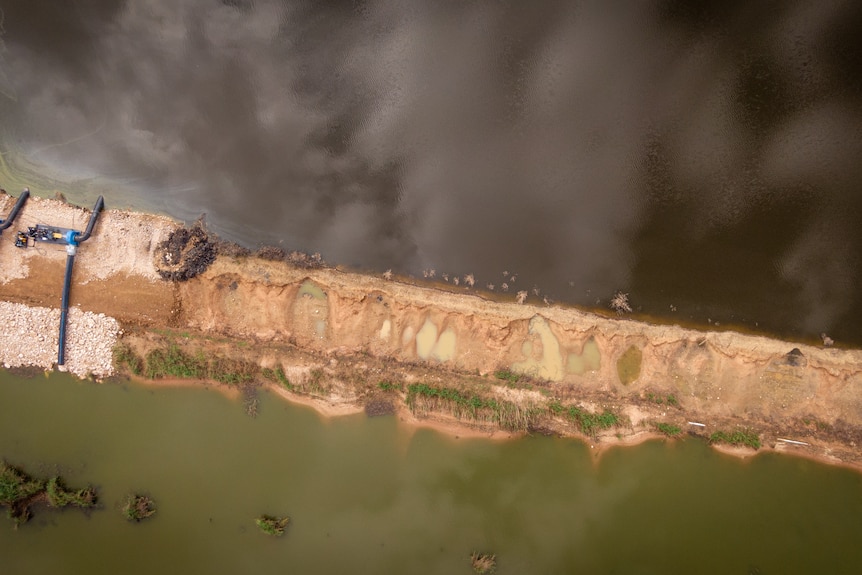 A drone image shows a sandbank separating two bodies of water.