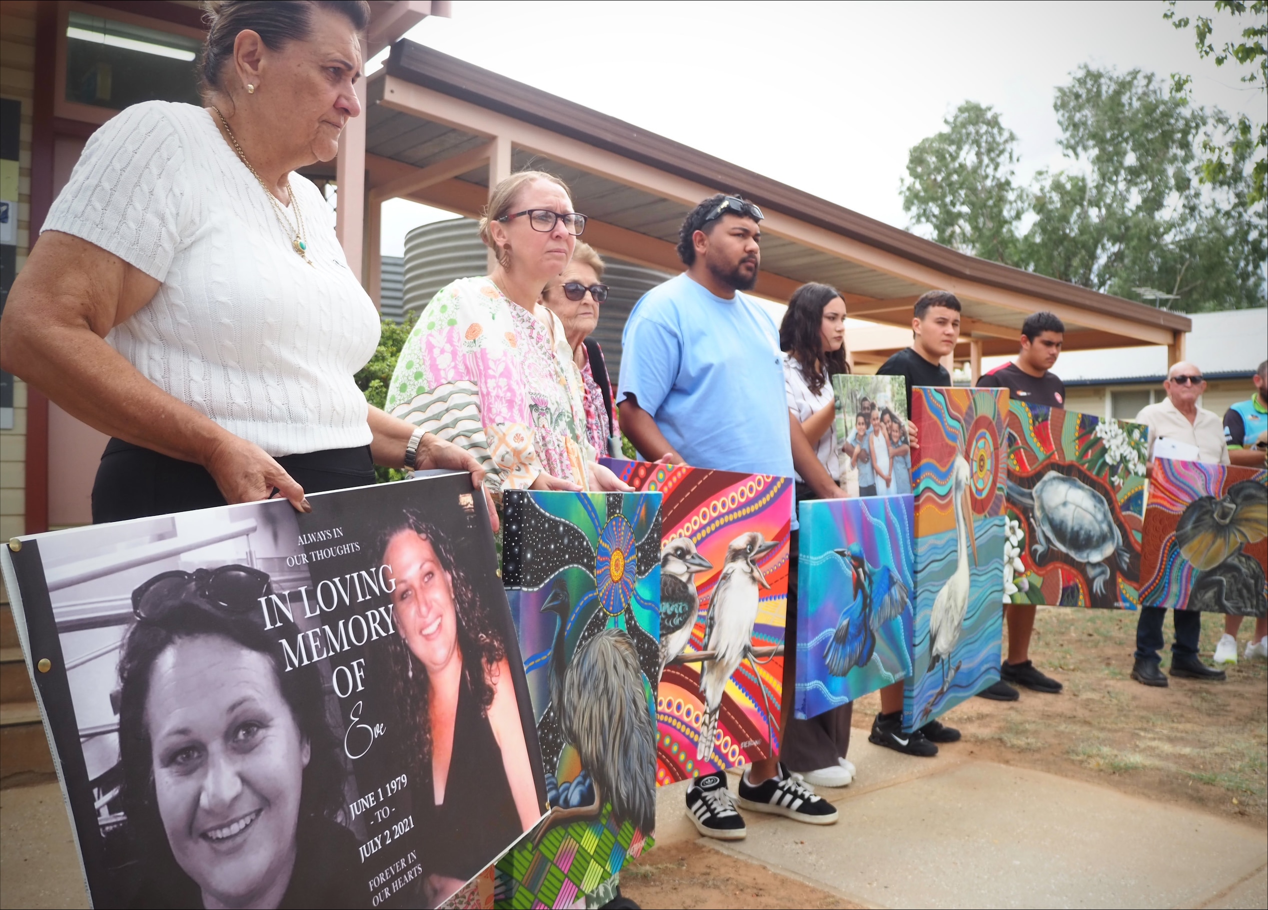 Miembros de la familia sostienen obras de arte indígenas afuera del juzgado. 