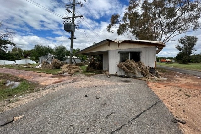 A flood damaged home with debris coming out the front window. 