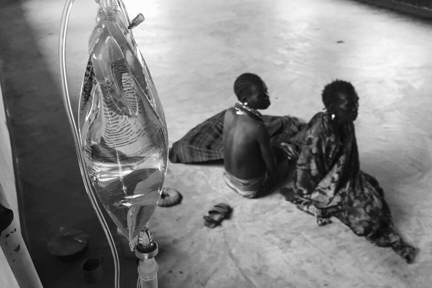 Four-year-old girl Nakor Lotollo, who is suspected to have cholera, is watched over by her mother and grandmother.