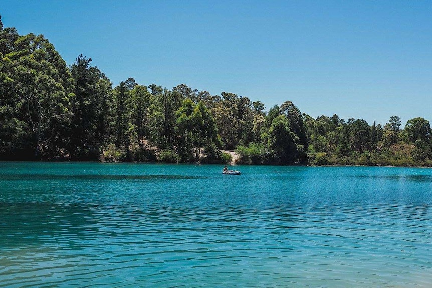 A picturesque, blue lake surrounded by native vegetation.