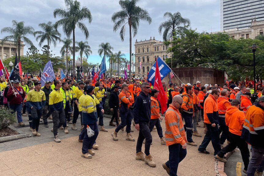 a large group of workers in high-vis shirts marching through brisbane city