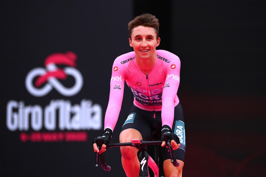 Jai Hindley aparece en la camiseta rosa del líder del Giro de Italia mientras cruza la línea de meta.