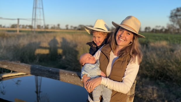 Kristy O'Brien with her sons Hudson and Nash (newborn) standing in front of a windmill