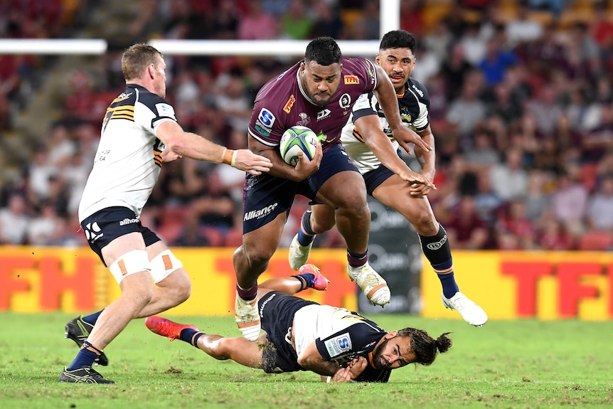 Taniela Tupou hurdles a player while carrying a rugby ball under his hand.