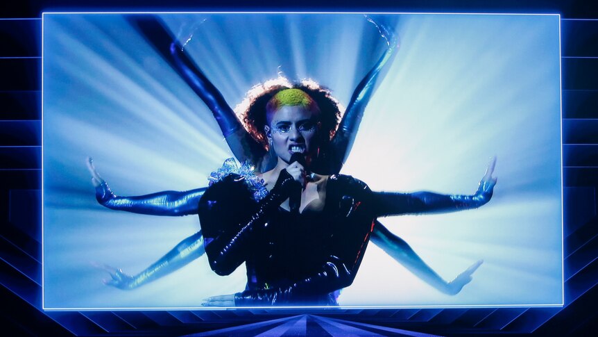 An Australian performer, Montaigne, performs at Eurovision via video, singing while flanked by backing dancers.